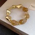Vista ravvicinata di un bracciale con perle irregolari in oro e resina ambra in stile vintage - Oro-Grigio
