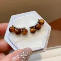 Close-up of retro silver needle earrings with shimmering brown resin beads. - Silver-Brown