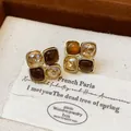 Close-up of asymmetric French vintage stud earrings with amber resin and champagne crystals - Gold-Amber