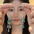 Detail view of ethnic style long tassel earrings with blue-green teardrop crystals - Gold/Blue