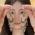 Ethnic style water-drop fringe earrings with colorful beads shown on an Asian model. - Gold/Green/Red