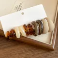 Detail view of retro acrylic earrings in amber and matte earth tones on white card - Multicolor