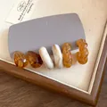 Detailed macro view of vintage acrylic marbled C-shaped earrings in Maillard tones set - Brown