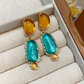 Detailed macro view of irregular oval resin drop earrings with amber and teal accents - Gold-Amber-Lake Blue