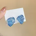 Unique blue irregular resin stud earrings with glitter texture shown on white card - Blue