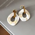 Dettaglio ravvicinato di orecchini geometrici in resina con motivo marmorizzato crema - Perno in argento-Bianco
