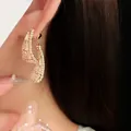 Primo piano di orecchini geometrici dorati vintage con strass scintillanti su modella - Stile Perno Argento - Strass Geometrico (4#) / Oro