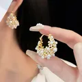 Primo piano di orecchini a cerchio vintage con perle e finitura dorata di classe - Stile Fibbia Orecchino - Grappolo di Perle Artificiali (16#) / Eco-Oro