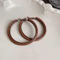 Detail macro view of vintage Maillard brown leather-wrapped hoop earrings on cream tray - Large Hoop Style