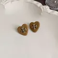 Detailed view of matte coffee brown heart-shaped earrings featuring a metallic cross - Heart Style