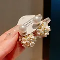 Primo piano di eleganti orecchini a fiore con perle e dettagli dorati rifiniti - Oro