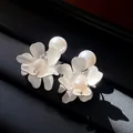 Close-up detail of vintage silver flower earrings with elegant freshwater pearls. - Silver