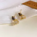 Detailansicht eleganter goldfarbener Trapez-Ohrstecker mit grauen und klaren Kristallen - Gold-Schwarz