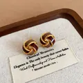 Detailed macro view of vintage knotted red and gold enamel stud earrings on a linen display card - 25# Silver Needle - Gold - Red - Brown