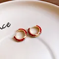 Macro detail of red and blue enamel gold hoop earrings on a beige ceramic plate - 52# Ear Buckle - Gold Red