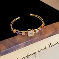Elegante bracciale rigido dorato con vivaci pietre di zirconia quadrata multicolore. - Bracciale rigido aperto in zirconia quadrifoglio (89#) / Oro