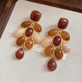 Primo piano dei dettagli degli orecchini vintage eleganti in resina marrone e oro - Stile Nappina Vintage Oro / Set con Perno in Argento 925 / Combo Marrone Ambra E Rosso