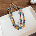 Close-up detail of a colorful bohemian irregular double-layered shell necklace on a tray - Colorful