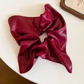 Close-up of a premium wine red leather scrunchie with a unique square pleated design - Burgundy