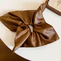 Close-up detail of a vintage brown faux leather square scrunchie for hair styling - Brown