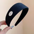 Primo piano di un cerchietto per capelli in tessuto nero con decoro ovale bianco elegante. - Stile Tessuto Texturizzato (HH8975) / Nero