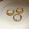Vista macro dettagliata di 3 anelli dorati regolabili con cuori e pietre scintillanti. - Oro (Set da 3 pezzi)