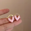 Detailopname van roze parelmoer hartvormige oorringen op vingers voor schaaldetails - 4# Gouden Ring Roze Parelmoer Hart Stijl