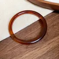 Detailed macro view of a vintage amber acetate bangle resting on a wooden surface - Amber