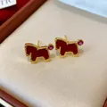 Detailed close-up view of gold-plated pony earrings with red enamel and pink zircon stones - Stud Earrings / Gold-Red