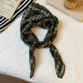 Close-up detail of a retro dark green paisley print silk scarf tied in a fashionable knot - Green Paisley