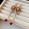 Close-up of vintage-style gold earrings with red stones and pearls on a beige tray - Red