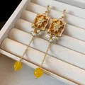 Close-up of vintage gold-tone earrings with floral relief, pearls and yellow beads. - Yellow