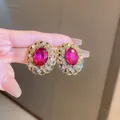 Close-up detail of vintage style earrings with pink oval gemstone and gold filigree. - Hollow Filigree Rose Red Studs