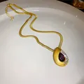 Gros plan d'un collier vintage doré avec pendentif en forme de goutte d'eau - Collier / Or