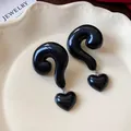 Detailed view of glossy black question mark earrings with dangling heart charms - Classic Black (Silver Post)