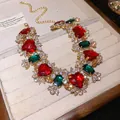 Dettaglio di una collana a cuore vintage con pietre rosse e verdi su vassoio di velluto - Collana / Oro-Rosso-Verde