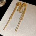 Close-up of 18k gold plated bead chain tassel ear clips on a gray display card - Clip-On Earrings / Gold