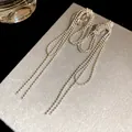 Close-up of elegant silver beaded chain tassel clip-on earrings on a textured gray display card - Clip-On Earrings / Silver