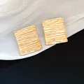 Close-up of gold rectangular earrings with elegant ripple texture finish - Gold
