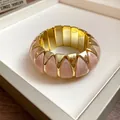 Close-up view of a pink marble acrylic and gold-tone geometric elastic stretch bracelet. - Elastic Geometric Style / Gold-Pink