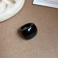 Anello in resina nera spessa con finitura lucida in un ambiente minimalista - Nero