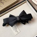 Détail d'une pince à cheveux en satin noir avec nœud papillon et strass brillants - Pince Crabe Nœud en Dentelle / Noir