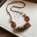 Détail d'un collier ethnique rétro en perles de résine aux tons ambrés et cordon cuir - Marron