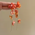 Close-up of orange chiffon flower earrings with long gold chain tassels held in hand. - Ear Clip-Orange Pink Layered Flower (7#)