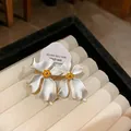 Primer plano de pendientes de flores blancas con pétalos mate y centro en oro - Plateado