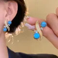 Close-up of vintage gold earrings with turquoise beads and sparkling cubic zirconia stones - Stud Earrings / Gold with Blue