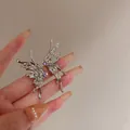 Eleganti orecchini a farfalla in metallo liquido argento con zirconi viola sulla mano - Zirconia Viola Metallo Liquido (33)