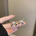 Eleganti orecchini a fiocco dorati con smalto nero, cristalli e una perla centrale - Fiocco di Perla Artificiale Nera (59)