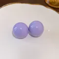 Primo piano di eleganti orecchini a lobo a sfera viola su un piatto di ceramica bianca - Viola