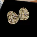 Detailed close-up of gold-plated oval hollow earrings with sparkling baguette zircons. - Oval Hollow Style (HE30145) / 925 Silver Needle / Gold